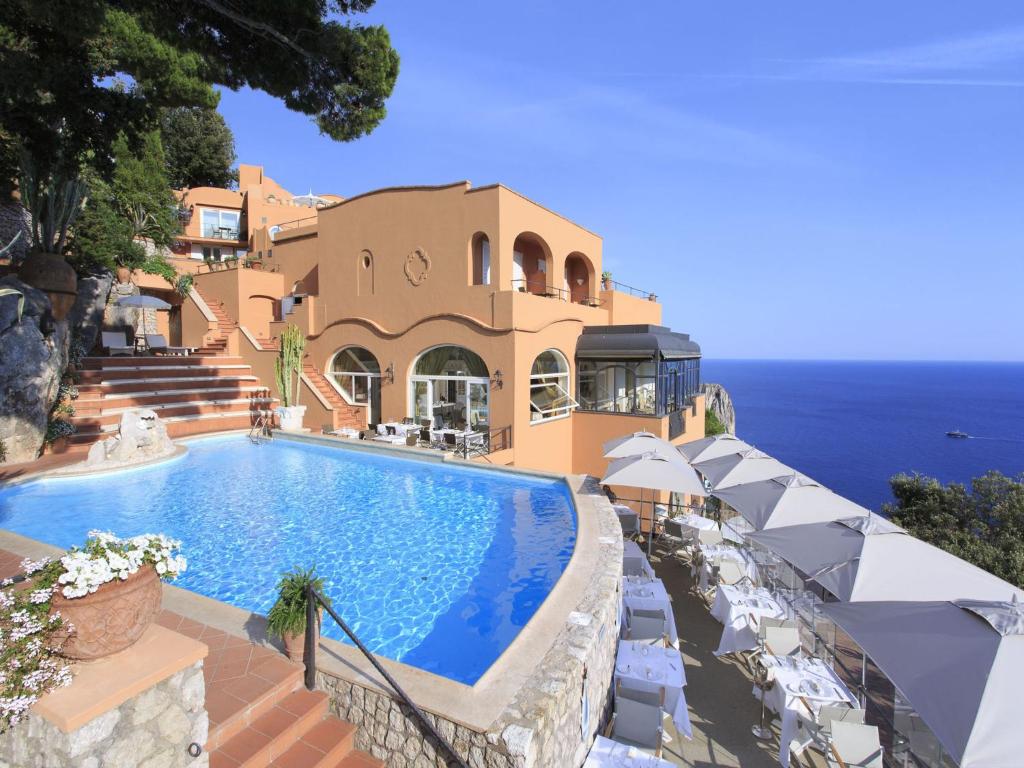 a house with a swimming pool next to the ocean at Hotel Punta Tragara in Capri