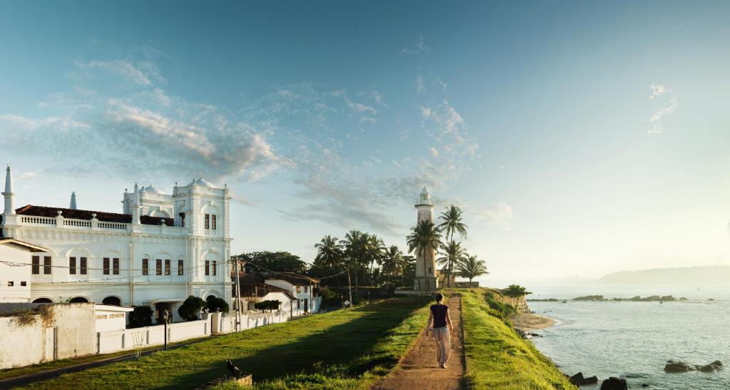 a man walking down a path next to a white house at Kahanda Kanda in Koggala