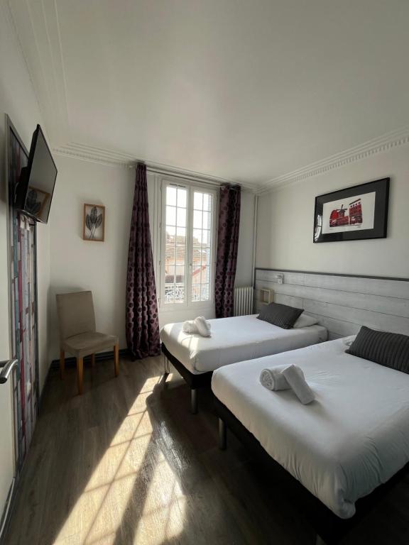 a room with two beds and a chair at Villa Liberté in Villejuif
