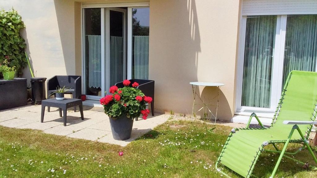 un patio avec une chaise verte et une plante en pot dans l'établissement Appartement charmant à Carentan les Marais, 40 m² avec terrasse, à Carentan