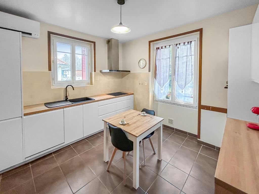 une cuisine avec des armoires blanches et une table en bois dans l'établissement Grand Jardin Maison Spacieuse Idéale pour Famille, à Larche