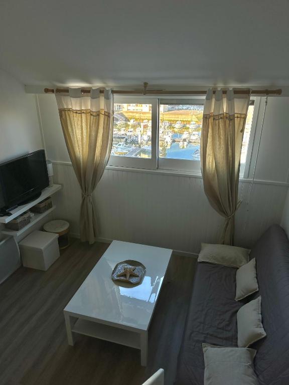 un salon avec un canapé et une table dans l'établissement Aux beaux coquillages, vue mer et sur le port, à Courseulles-sur-Mer