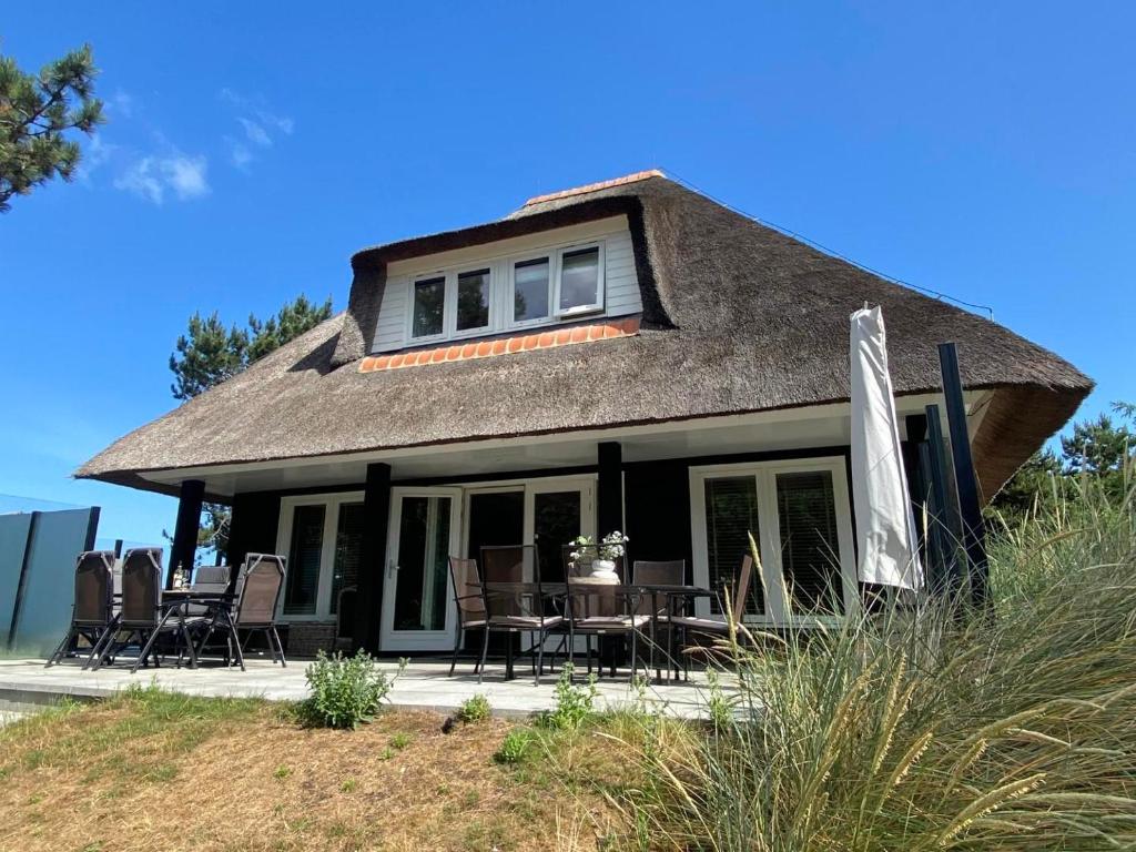 a house with a thatched roof with a table and chairs at Bosch (10p) in Buren