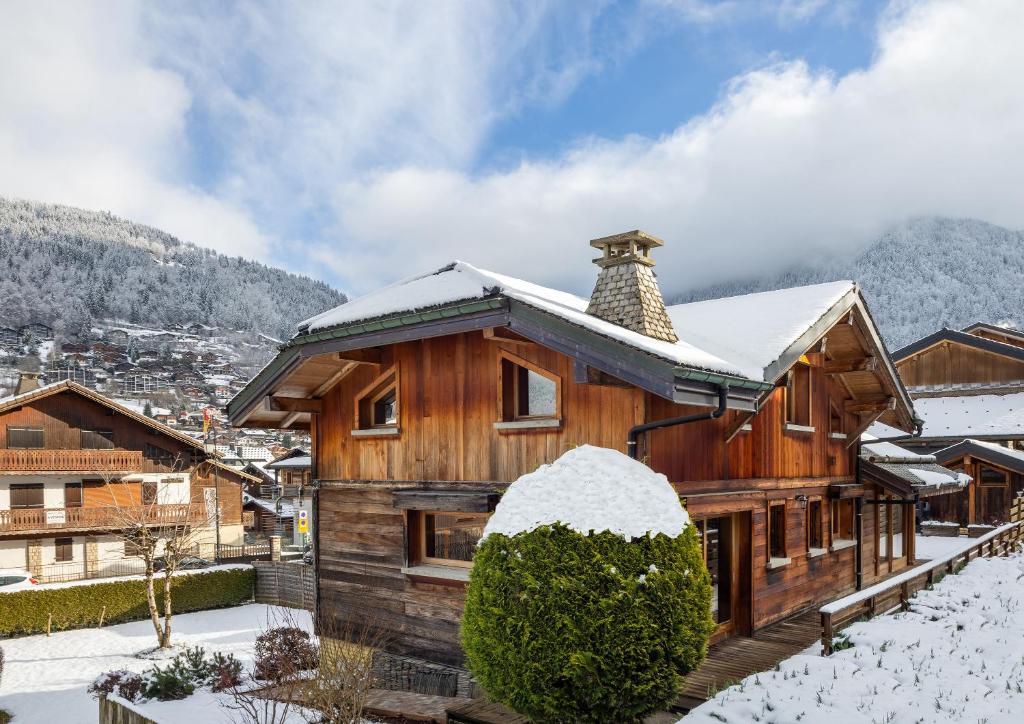 une maison en bois avec de la neige sur le toit dans l'établissement Simply Morzine - Chalet Visage, à Morzine