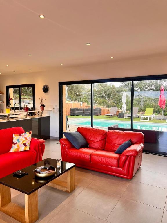 un salon avec un canapé rouge et une table dans l'établissement Maison Terra Bella, expérience authentique en plein cœur du maquis, piscine, à Sotta