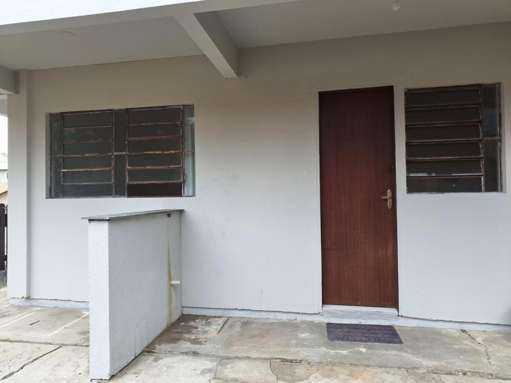 a white building with a brown door and windows at Casa até 4 pessoas Rua Corrupiao Bombas in Bombinhas