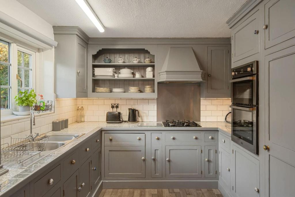 eine Küche mit weißen Schränken und einer Spüle in der Unterkunft 17th Century Cottage in Bideford Private Parking in Bideford