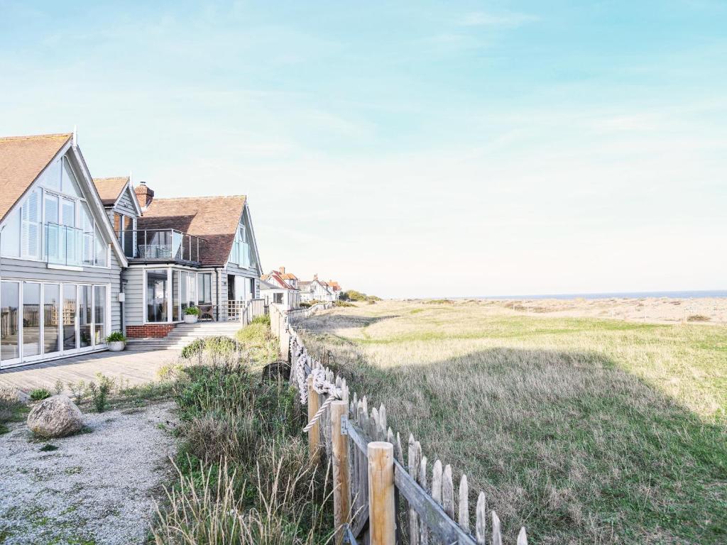 una casa con una valla al lado de un campo en Spinneys Beachfront by The Suffolk Cottage Collection, en Thorpeness