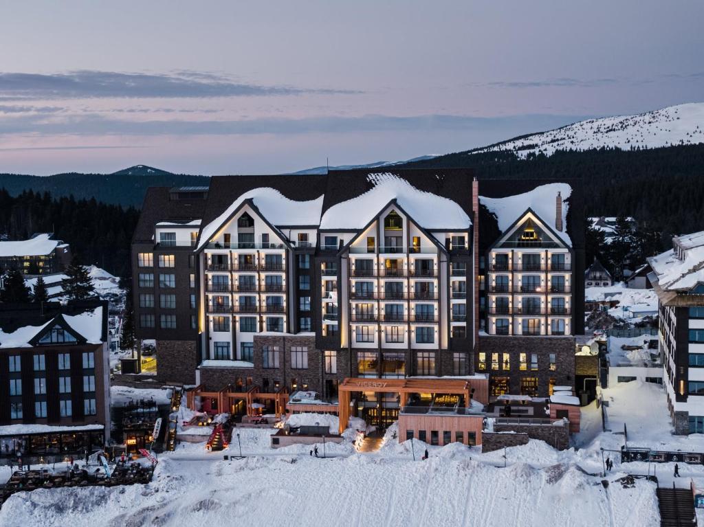 a large building with snow on top of a town at Viceroy Kopaonik Resort & Spa in Kopaonik