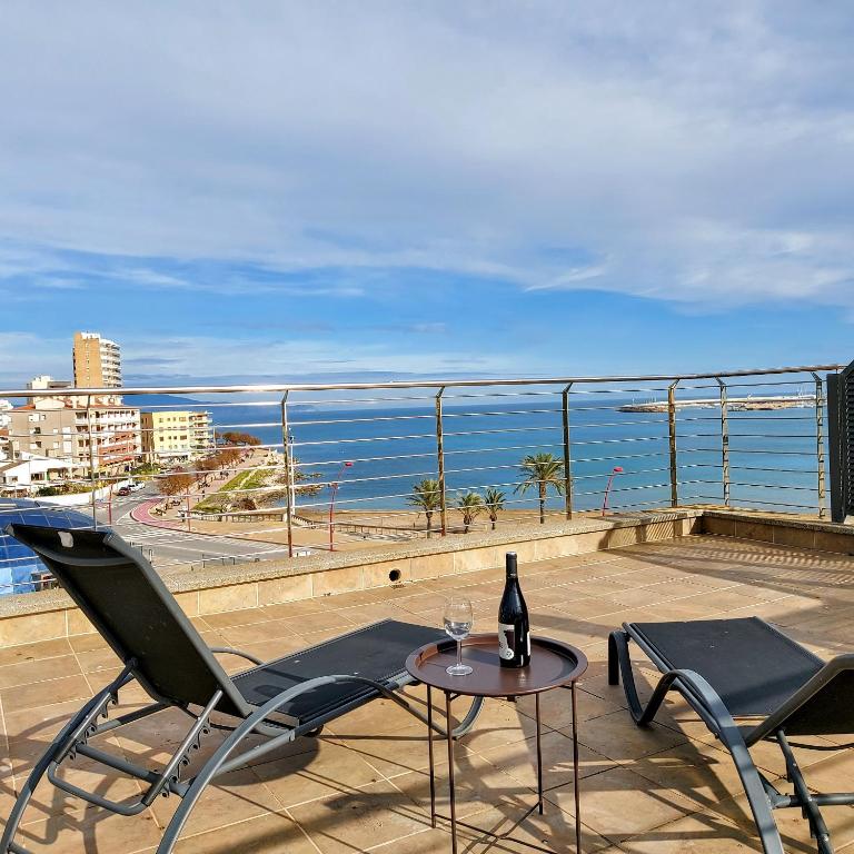 a table and chairs on a balcony with a bottle of wine at Duplex Univers - Frente al mar in L'Escala