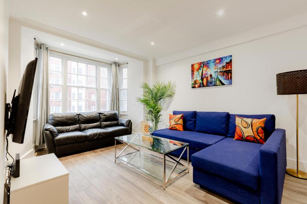 a living room with a blue couch and a glass table at Central Apartments near Marble Arch in London