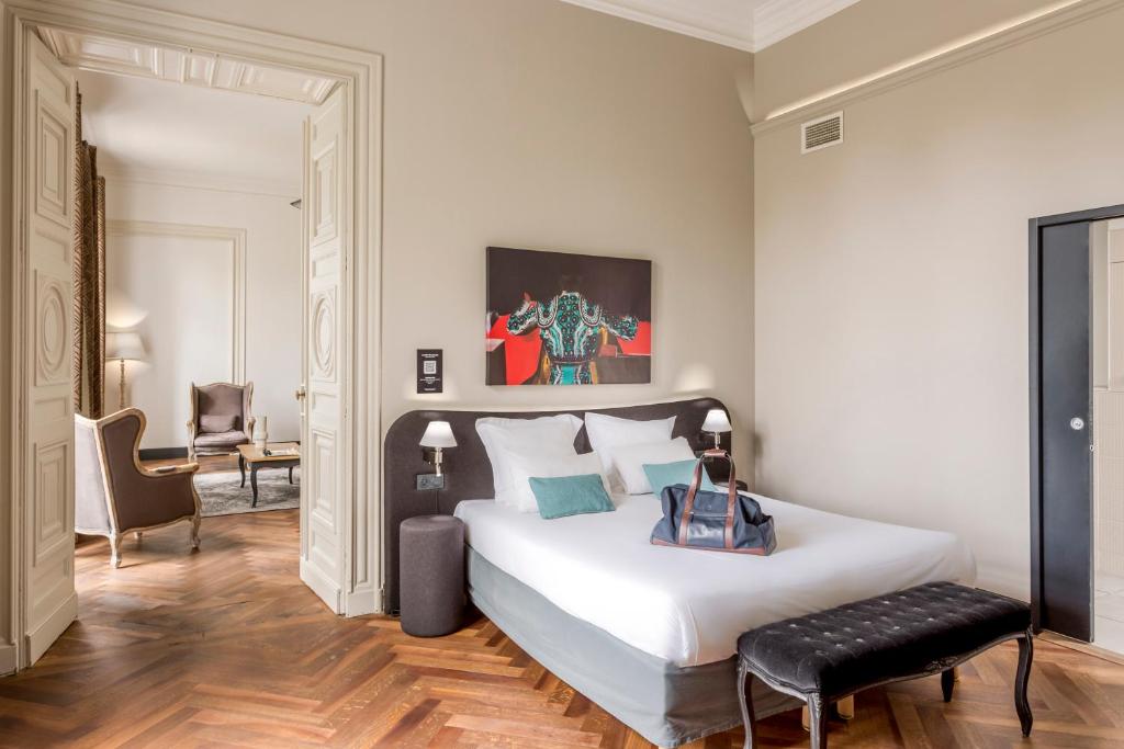 une chambre avec un grand lit blanc et une chaise dans l'établissement Appart'City Collection Nîmes Arènes, à Nîmes
