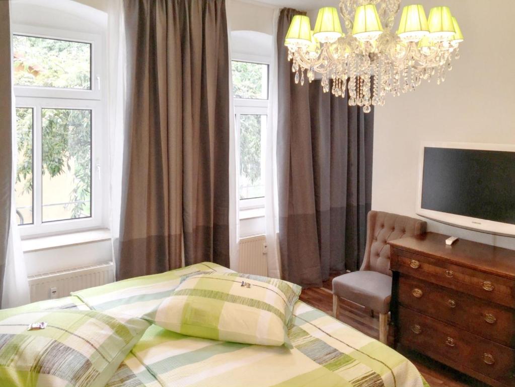 エアフルトにあるCozy apartment in the heart of Erfurt 30 m² city viewのベッドルーム(ベッド1台、テレビ、シャンデリア付)