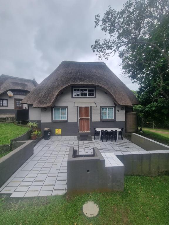 a house with a thatched roof with a patio at Hibberdene Cottage Crew in Hibberdene