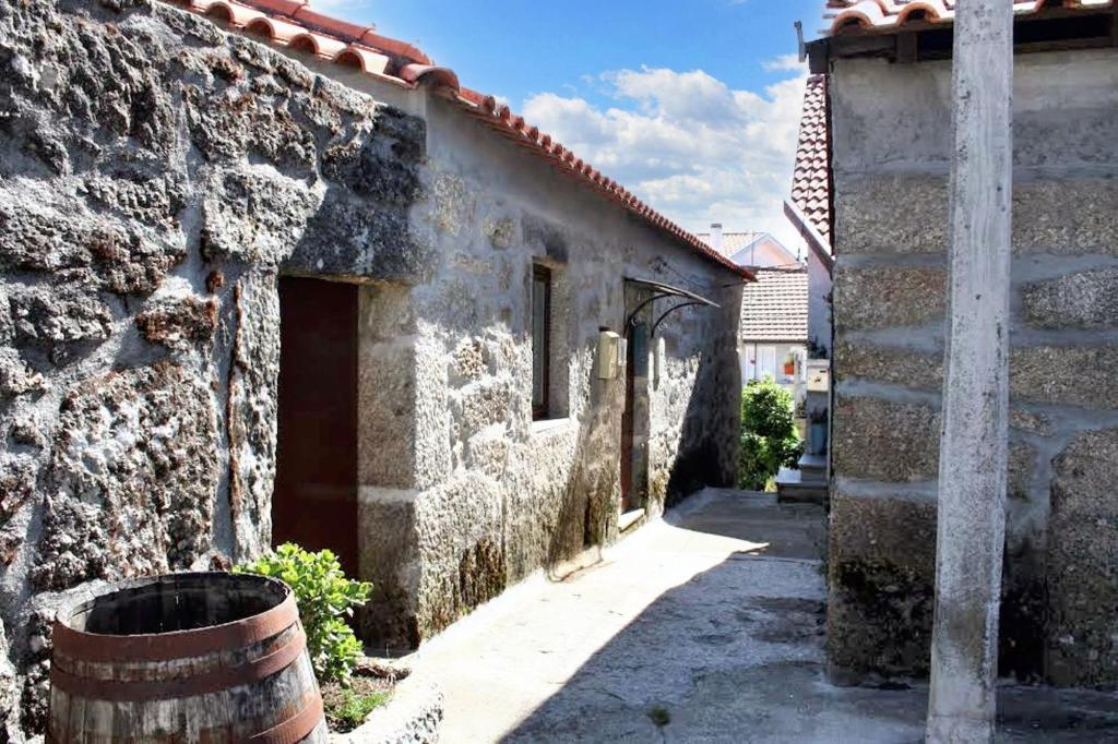 un vieux bâtiment en pierre avec un tonneau à côté dans l'établissement Spacious Family House in Nogueira with Garden, à Moita