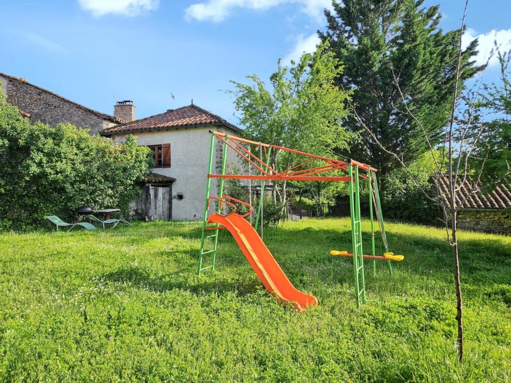 a playground with an orange slide in a yard at Maison conviviale à Peyrusse le Roc, avec jardin sans vis-à-vis in Peyrusse-le-Roc
