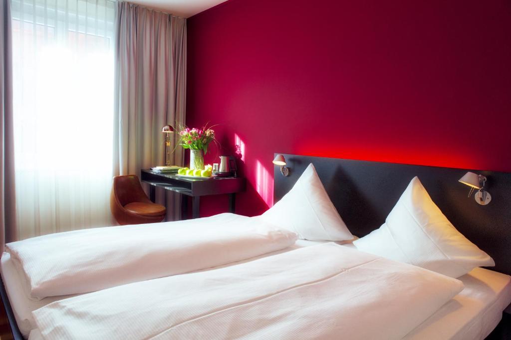 um quarto com 2 camas brancas e uma parede vermelha em Hotel Montana Zürich em Zürich