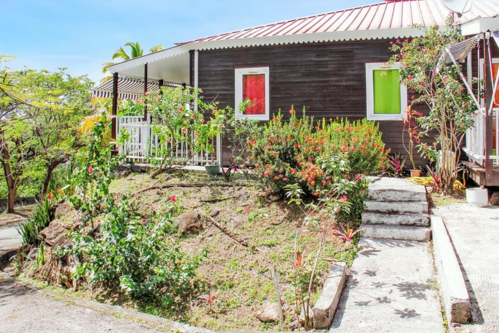 a garden in front of a house with flowers at Bungalow accueillant à Bouillante avec climatisation et terrasse in Bouillante