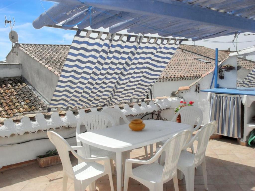 Biały stół i krzesła na patio z niebieskim parasolem w obiekcie Maison accueillante à Saintes-Maries-de-la-Mer, 110 m², climatisée. w Saintes-Maries-de-la-Mer