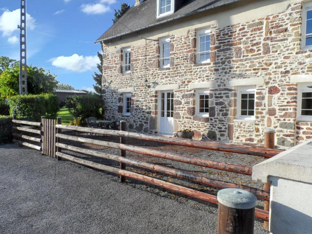 a wooden fence in front of a stone house at Maison charmante près de Chanteloup avec terrasse. in Chanteloup