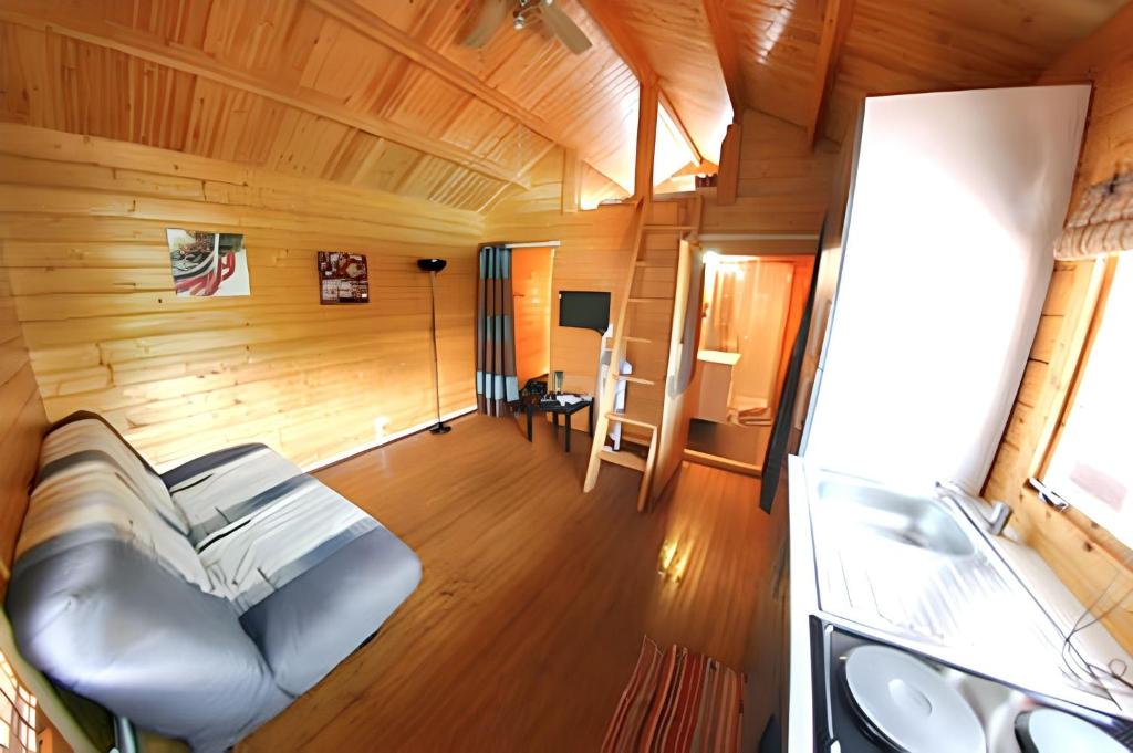 a living room with a couch in a wooden room at Bungalow charmant à Saint-Joseph, vue sur la piscine in Saint-Joseph