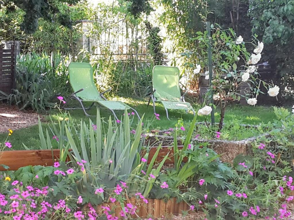 - deux chaises vertes dans un jardin fleuri dans l'établissement Appartement charmant à Villeneuve avec jardin, à Villeneuve-dʼAveyron