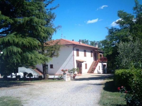 a large white house with a tree and a driveway at Podere Il Fattoio in Figline Valdarno