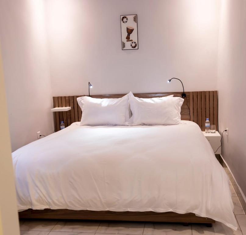 a bed with white sheets and pillows in a room at Lux Inn App in Kigali