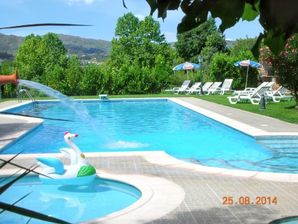 a swan swimming in a pool with a fountain at Comfortable house with mountain view and shared pool in Pedraça