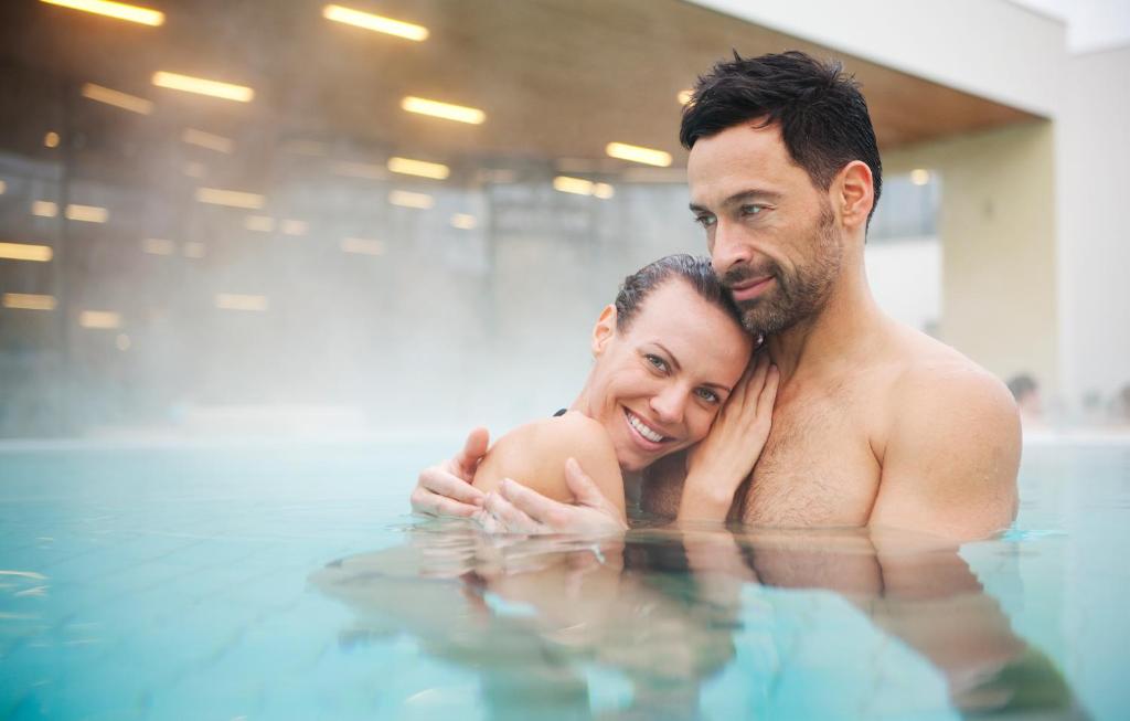 a man and a woman in the swimming pool at Vitalhotel der Parktherme - inkl Thermeneintritt & Sauna in Bad Radkersburg