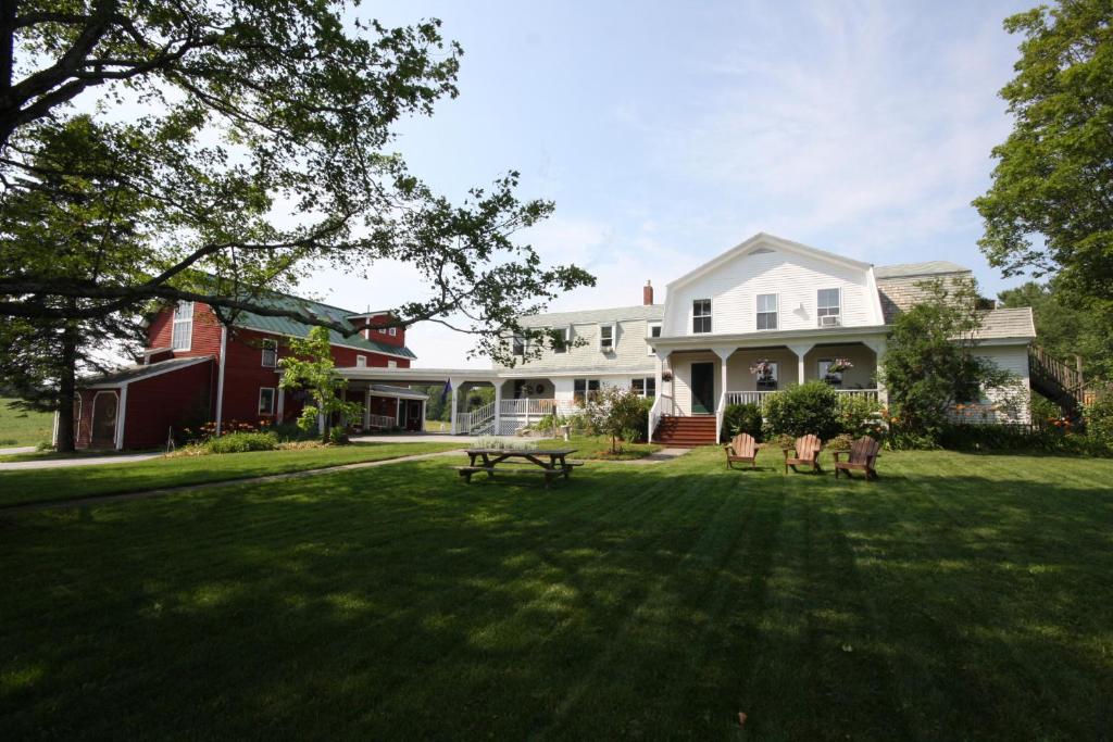 ein großer Garten mit einem Picknicktisch vor einem Haus in der Unterkunft Maple Hill Farm Inn in Augusta