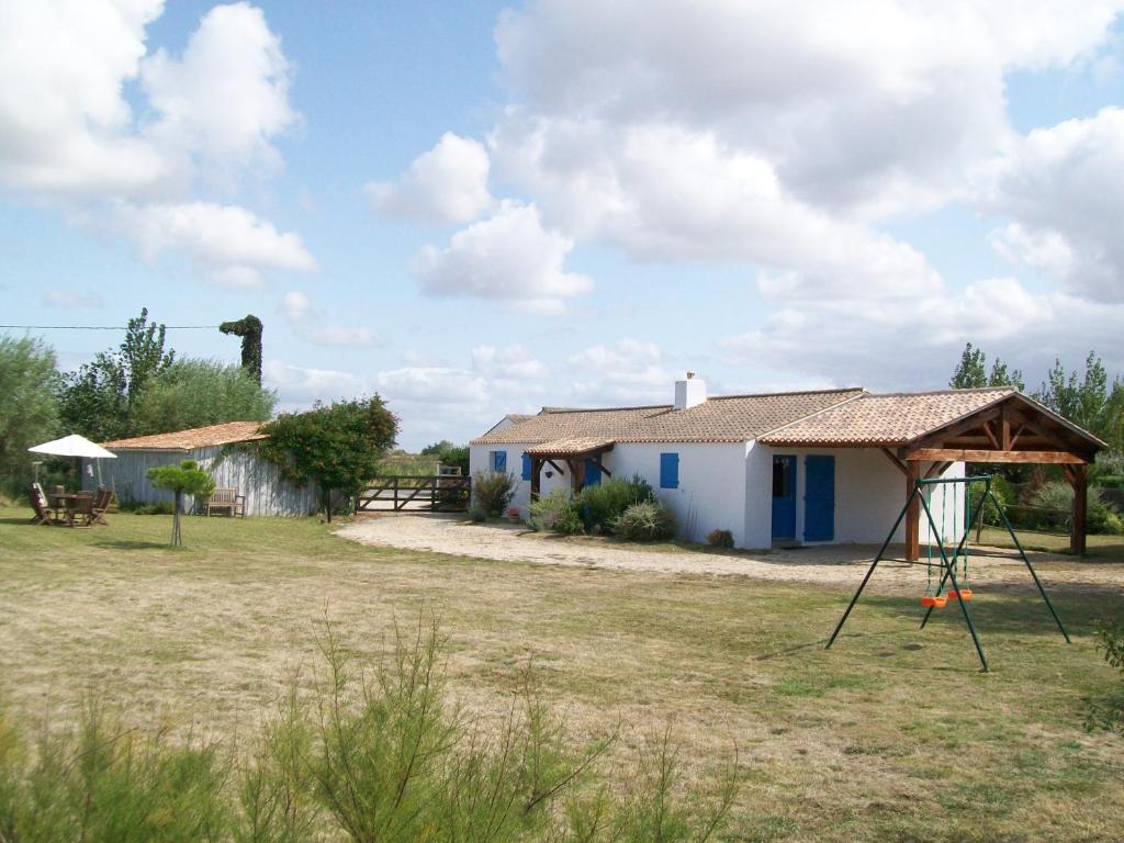 una pequeña casa blanca con un cenador en un campo en Gîte de La Jolette, en Saint-Jean-de-Monts