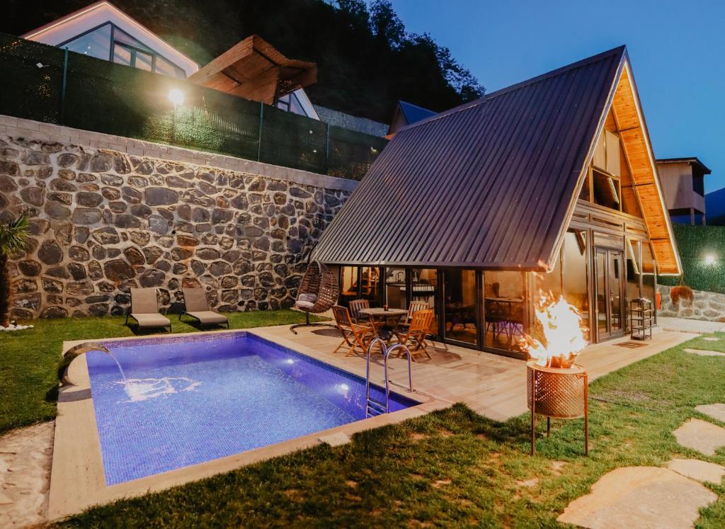 a house with a swimming pool next to a stone building at Tina Bungalov in Sapanca