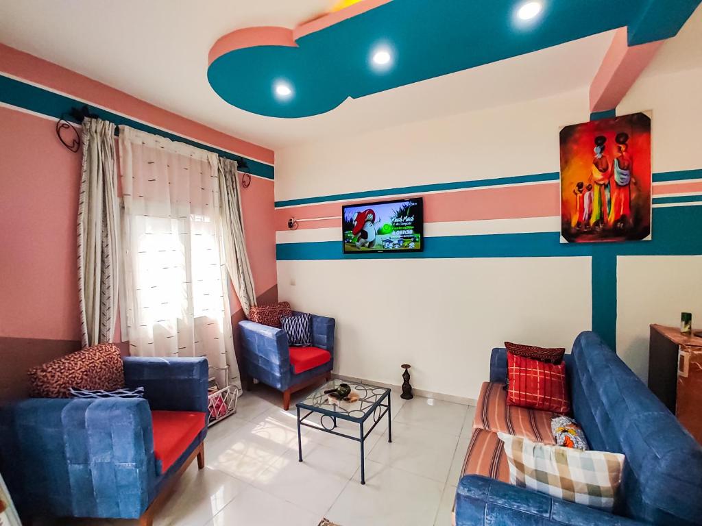 a living room with striped walls and blue chairs at MOOKSQUARE GJ SPOT in Douala