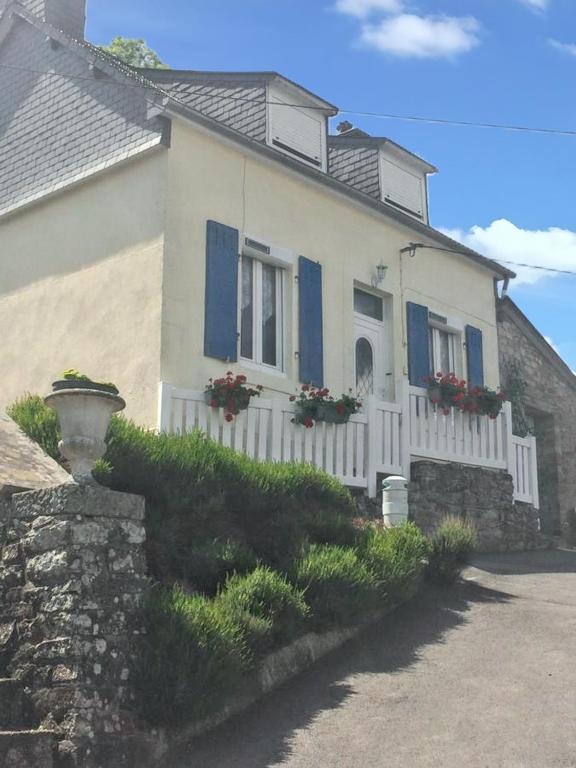 une maison blanche avec volets bleus et fleurs sur elle dans l'établissement Maison confortable à Châteaulin avec jardin et terrasse., à Châteaulin