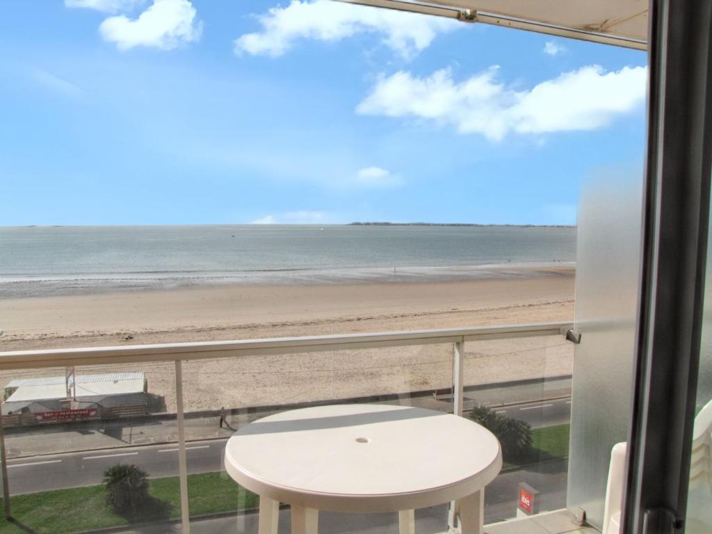 a view of the beach from a balcony with a table at Charmant studio vue mer à Pornichet 30 m² avec terrasse in Pornichet
