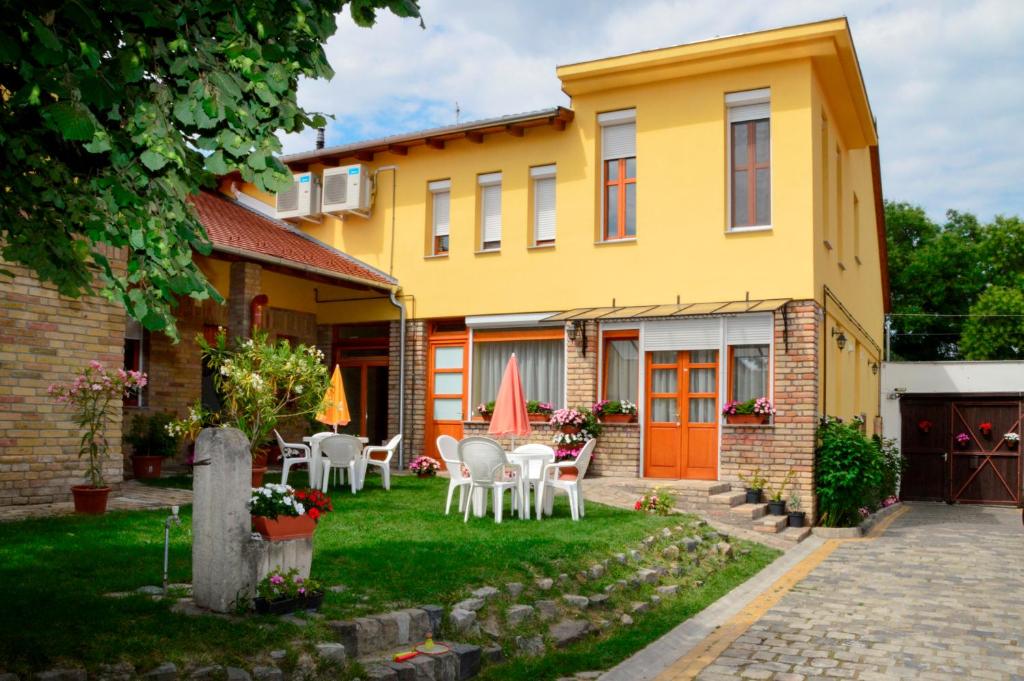 żółty dom ze stołami i krzesłami na dziedzińcu w obiekcie Mediterrán Vendégház w mieście Kecskemét