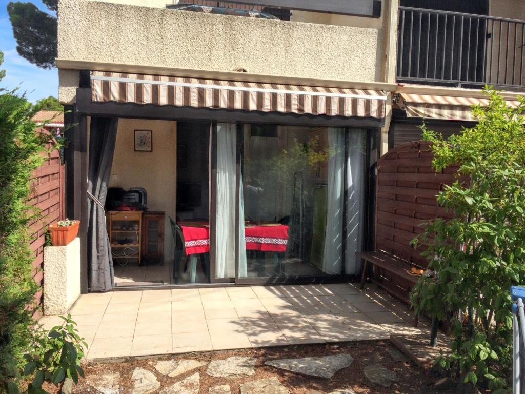 a sliding glass door of a house with a table at Charmant appartement avec piscine partagée à Agde in Cap d'Agde
