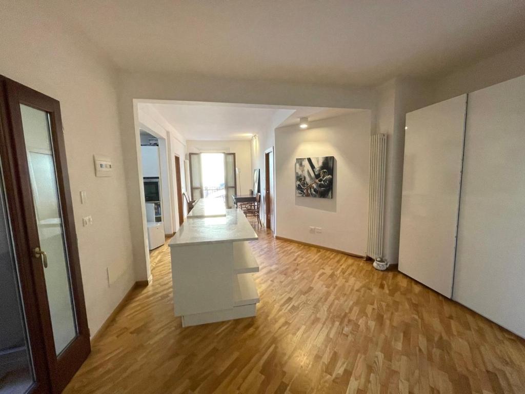 pusty salon z drewnianą podłogą i białymi ścianami w obiekcie Loft del Pratello w Bolonii