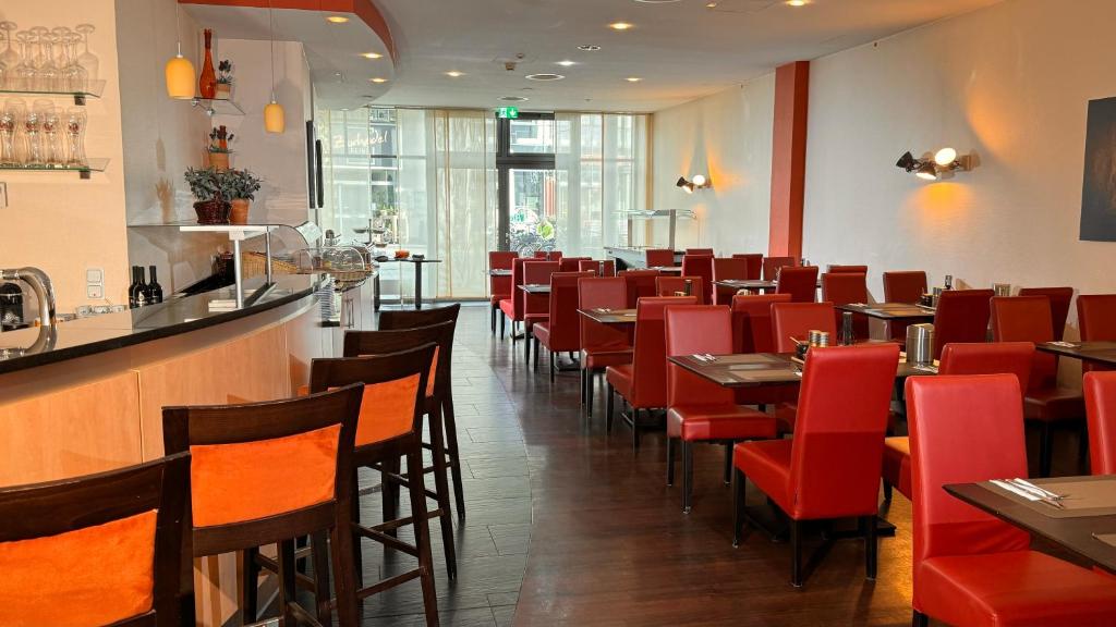 ボトロップにあるHotel Rhein-Ruhr Bottropの赤い椅子とバー付きのダイニングルーム