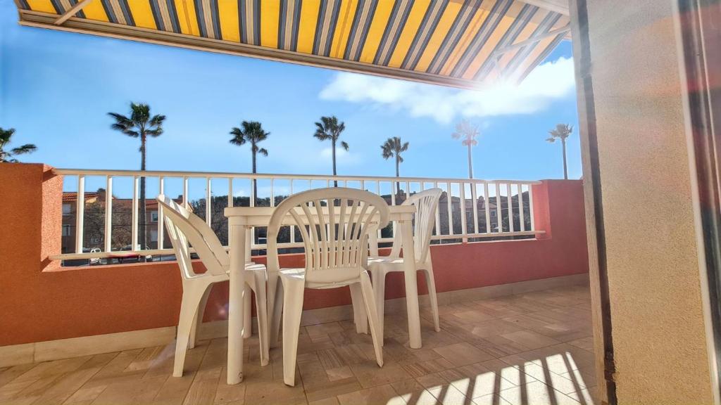 d'une table et de chaises sur un balcon avec des palmiers. dans l'établissement Studio confort à Hyères - 20 m² avec barbecue et terrasse, à Hyères