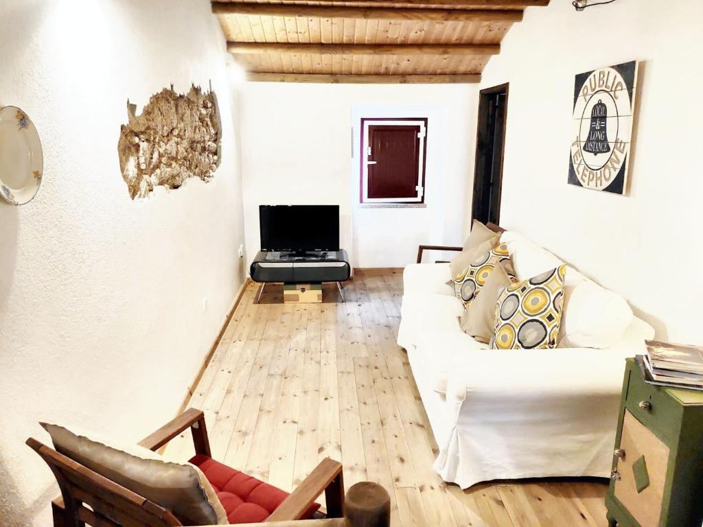 a living room with a white couch and a tv at Charming House in Beirã with Garden in Beirã