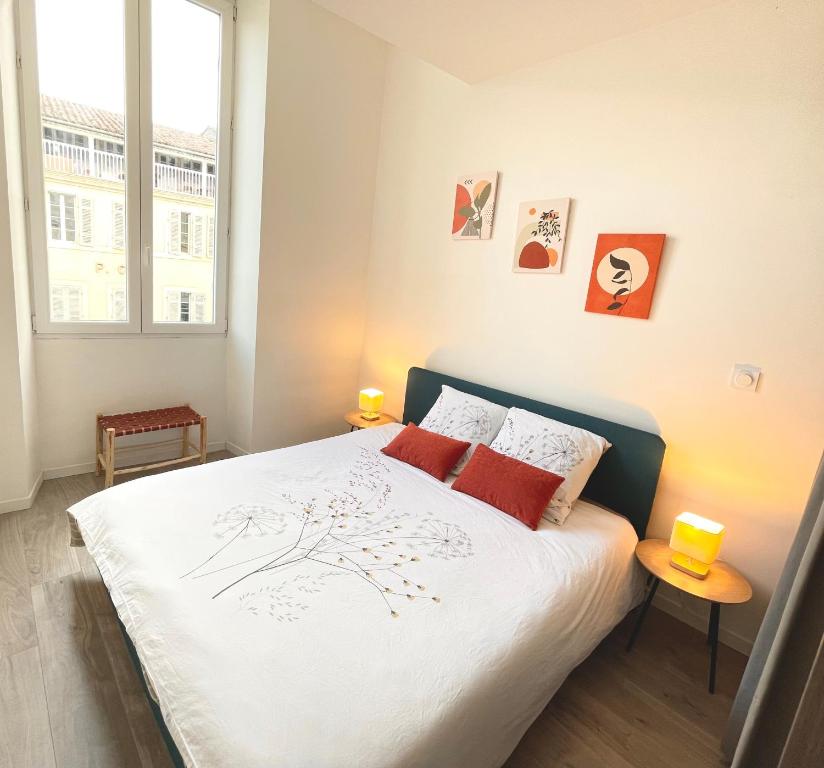 a bedroom with a bed with white sheets and red pillows at L'Ibéris - Toutes les commodités dans la rue - 1er étage in Auch