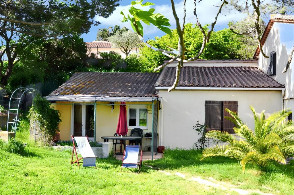a small white house with a table in the yard at Maison confortable à Berriac, 80 m² avec jardin privé in Berriac