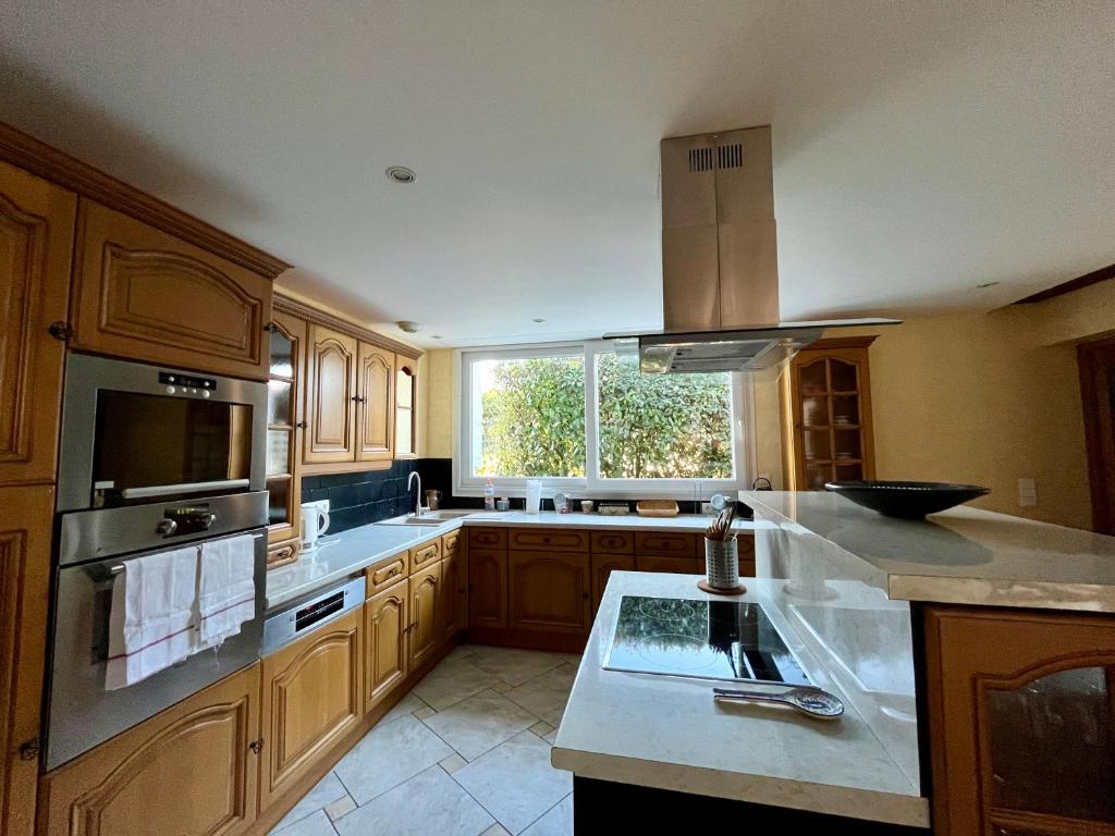 a kitchen with wooden cabinets and a large window at Les Romarins in Vallières-les-Grandes