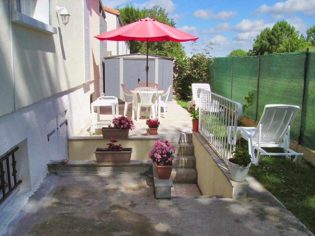 a patio with a table and chairs and an umbrella at Appartement charmant à Breuillet avec jardin spacieux in Breuillet