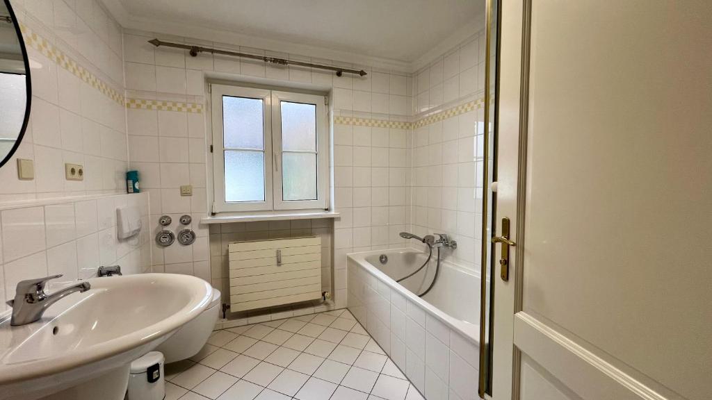ein weißes Badezimmer mit einer Badewanne und einem Waschbecken in der Unterkunft Sunset I Lakeview I BBQ ღLiboria in Herrsching am Ammersee