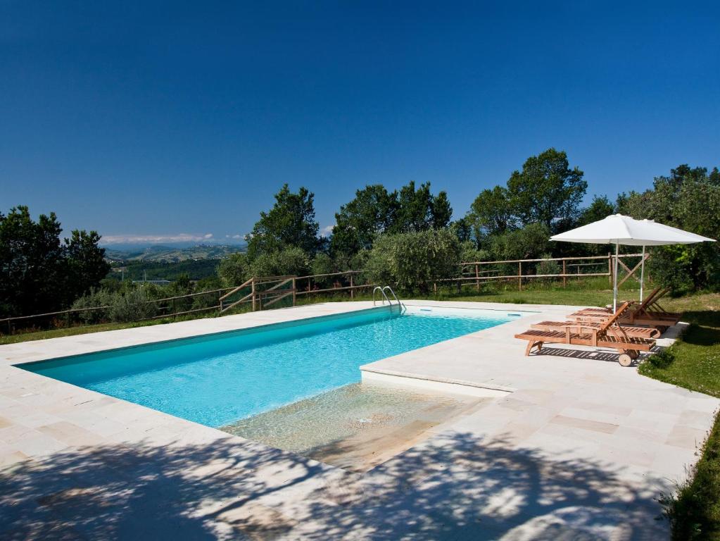 - une piscine avec un parasol, deux chaises et une table dans l'établissement I Sassi Di San Giuseppe, à Montegiorgio