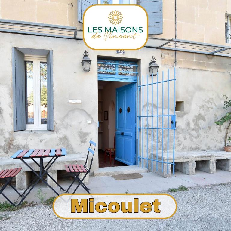 un bâtiment avec une porte bleue, une table et des chaises dans l'établissement Micoulet, Parking - Clim, à Arles