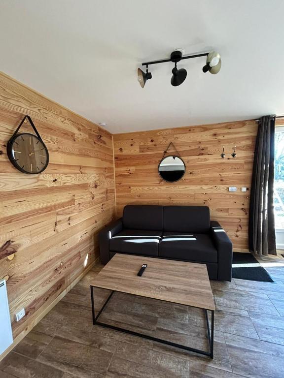 - un salon avec un canapé noir et une table basse dans l'établissement Maison au calme à l'orée du bois, à Lunery